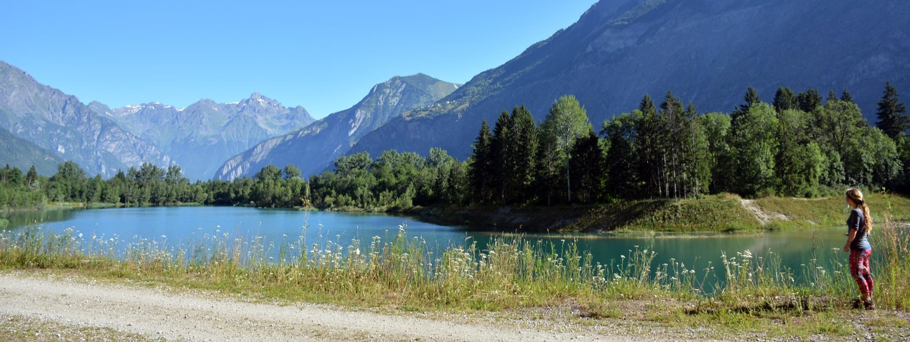 Lac du buclet qui se trouve à Bourg d'Oisans au premier plan avec un personne et les montagnes en arrière plan